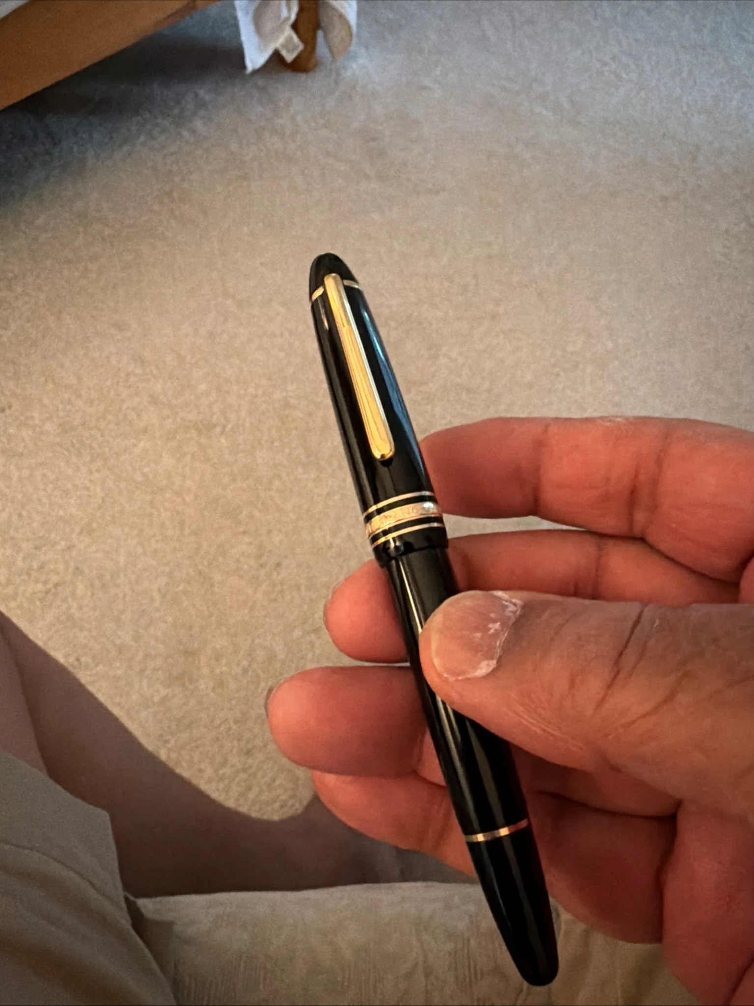 Black fountain pen with gold-tone clip and trim held in hand with the cap on